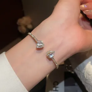 Close-up of a gold-plated cuff bracelet featuring sparkling zircon heart-shaped crystals