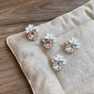 Dettaglio di eleganti orecchini a fiore bianco con grandi zirconi rosa e trasparenti.