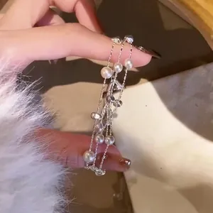 Vista de cerca detallada de una elegante pulsera multicapa con perlas y cuentas plateadas.