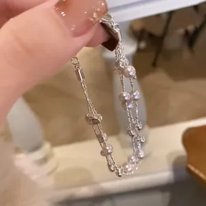 Primer plano detallado de una elegante pulsera de perlas multicapa sostenida en la mano