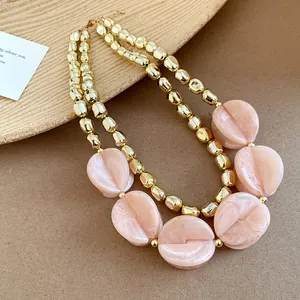 Detailed close-up of double-layered acrylic necklace with peach marble and gold beads