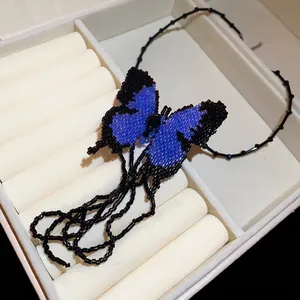 Handmade blue beaded butterfly tassel necklace for women, stylish choker on jewelry box.