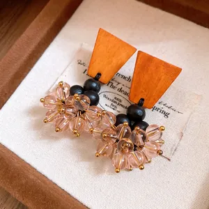 Détail rapproché de boucles d'oreilles ethniques en bois avec glands de perles roses