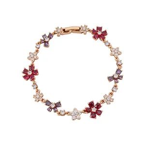 Elegant gold plated zircon bracelet with colorful flower and bow charms on white background