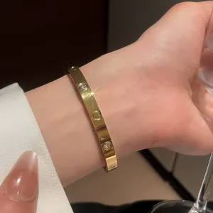 Macro view showing the heart engraving and zircon detail of the gold bangle bracelet