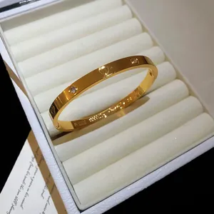 Close-up of a gold-toned bangle with heart and zircon details in a white jewelry box