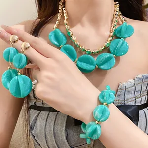 Close-up detail of a turquoise marbled acrylic jewelry set with gold-toned necklace and bracelet