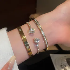 Macro view of three stacked gold-tone bangles with heart-shaped zircons and pave stones.