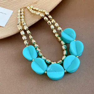 Macro view of cyan acrylic pleated beads on a double-layer golden chain necklace