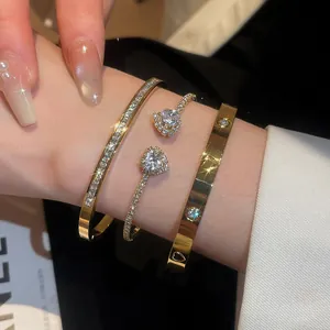 Close-up detail of luxury gold bangles set with sparkling heart zircons on a model's wrist.