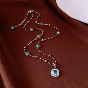 Close-up detail of light blue cushion cut pendant necklace on brown fabric background
