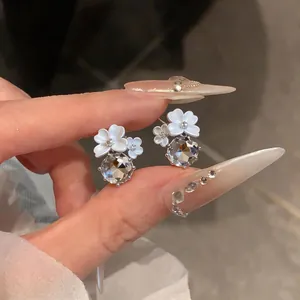 Primo piano di eleganti orecchini a fiore bianco con grandi pendenti in zircone
