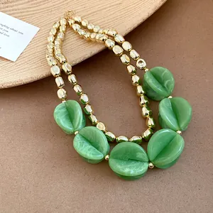 Close-up detail of double-layer necklace with green acrylic beads and gold metallic accents