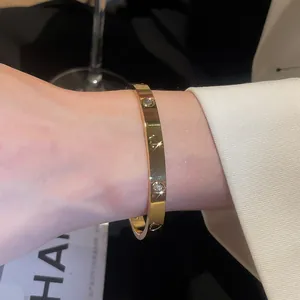 Elegant gold-plated bangle featuring heart engravings and sparkling zircon stones on a wrist.