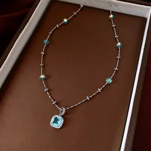 Detailed macro view of an elegant square light blue zircon pendant necklace in a box