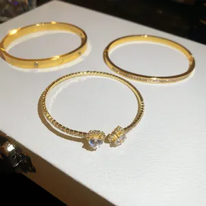 Detail view of gold-plated bracelets featuring heart-shaped zircon settings and engravings