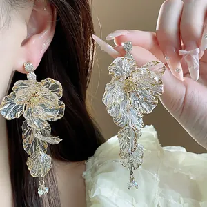 Detailaufnahme eleganter Acrylblumen-Ohrringe mit Goldrand und funkelnden Strasssteinen