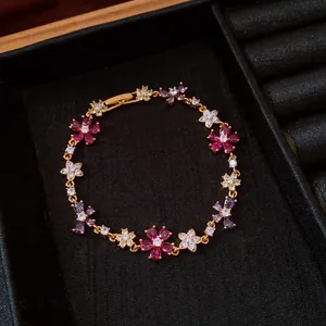 Close-up of a gold plated bracelet with colorful zircon flower patterns in a jewelry box.