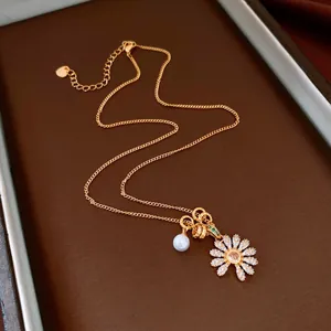 Détail du pendentif fleur en zircone étincelante et de l'élégant collier avec perle blanche.