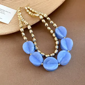 Detailed view of luxury double-layered necklace with blue acrylic beads and gold finish