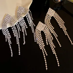 Close-up of sparkling silver and gold rhinestone tassel earrings on a dark surface.