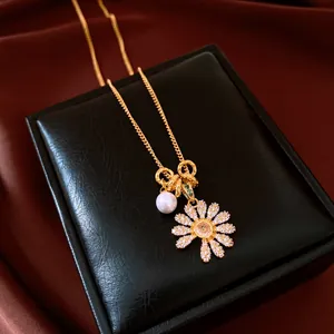 Vue détaillée d'un collier vintage doré avec fleur en zircone scintillante et perle élégante