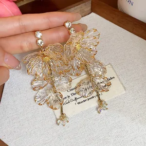 Detailansicht eleganter floraler Acrylohrringe mit Goldakzenten und funkelnden Kristallen