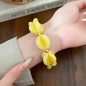 Close-up detail of a chunky yellow acrylic spliced bead bracelet with gold accents