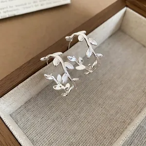 Minimalist C-shaped silver hoop earrings featuring a brushed leaf branch design for women