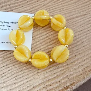 Detail view of yellow acrylic bead bracelet with gold-toned spacers and unique split design