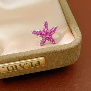 Vue macro détaillée d'un clip d'oreille étoile de mer en zircon rose sur un écrin