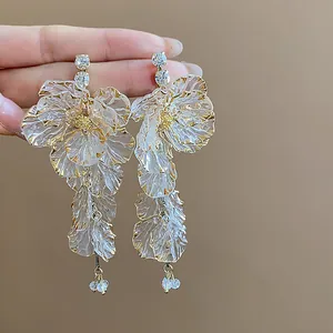 Detailansicht eleganter Acryl-Blütenohrringe mit Strasssteinen und goldfarbenem Rand.