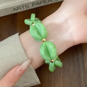 Close-up of a vibrant green acrylic beaded bracelet on a wrist with golden accents