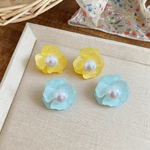 Detailed view of yellow and light blue flower earrings with white pearls on a display tray
