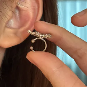 Close-up of sparkling cubic zirconia star ear cuff held near the ear for non-pierced ears