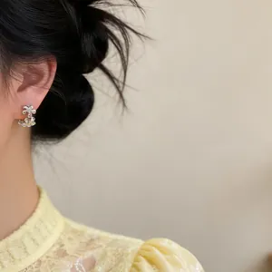 Macro detail of elegant silver-toned zircon floral hoop earrings worn by a model
