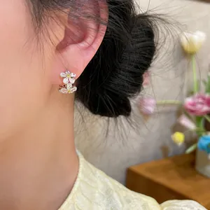 Close-up of elegant silver flower hoop earrings with yellow zircon centers.