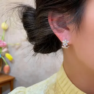 Close-up of a delicate zircon flower stud earring worn on the ear for a sweet look