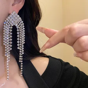 Detailed macro view of elegant silver rhinestone rhombus tassel dangle earrings on ear