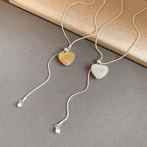 Detail of hollow mesh heart pendants on adjustable snake chains in gold and silver.