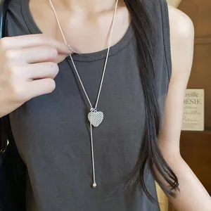 Detailed shot of a silver heart-shaped hollow lariat necklace worn on a model.
