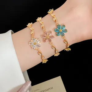 Détail macro de bracelets plaqués or 18 carats avec fleurs en zircon blanc, rose et bleu