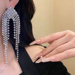 Close-up detail of elegant silver fringe earrings with sparkling rhinestones on a model