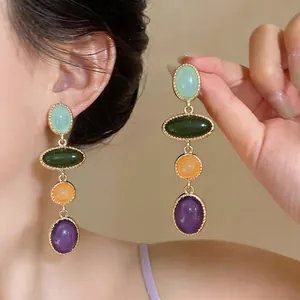 Detail view of vintage colorful resin oval drop earrings with gold-toned borders.
