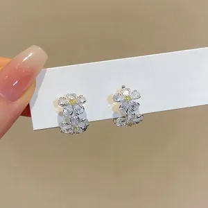 Detailed close-up view of dainty zircon flower ear buckles with yellow centers