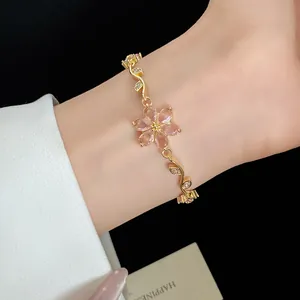 Détail d'un bracelet plaqué or 18k avec fleur en zircone rose sur poignet féminin