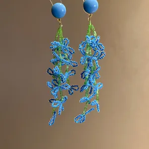 Exquisite detail of blue and green glass bead flower tassel earrings with silver pins