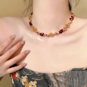 Close-up detail of a handmade beaded necklace with delicate red and orange floral patterns.