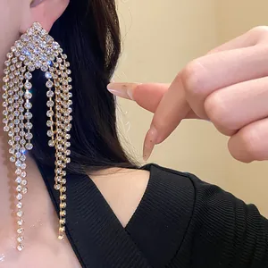 Detail view of high-end luxury sparkling rhinestone fringe drop earrings on ear.