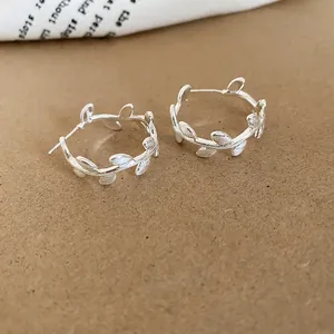 Macro view of the C-shaped branch earrings showing the brushed metal matte texture